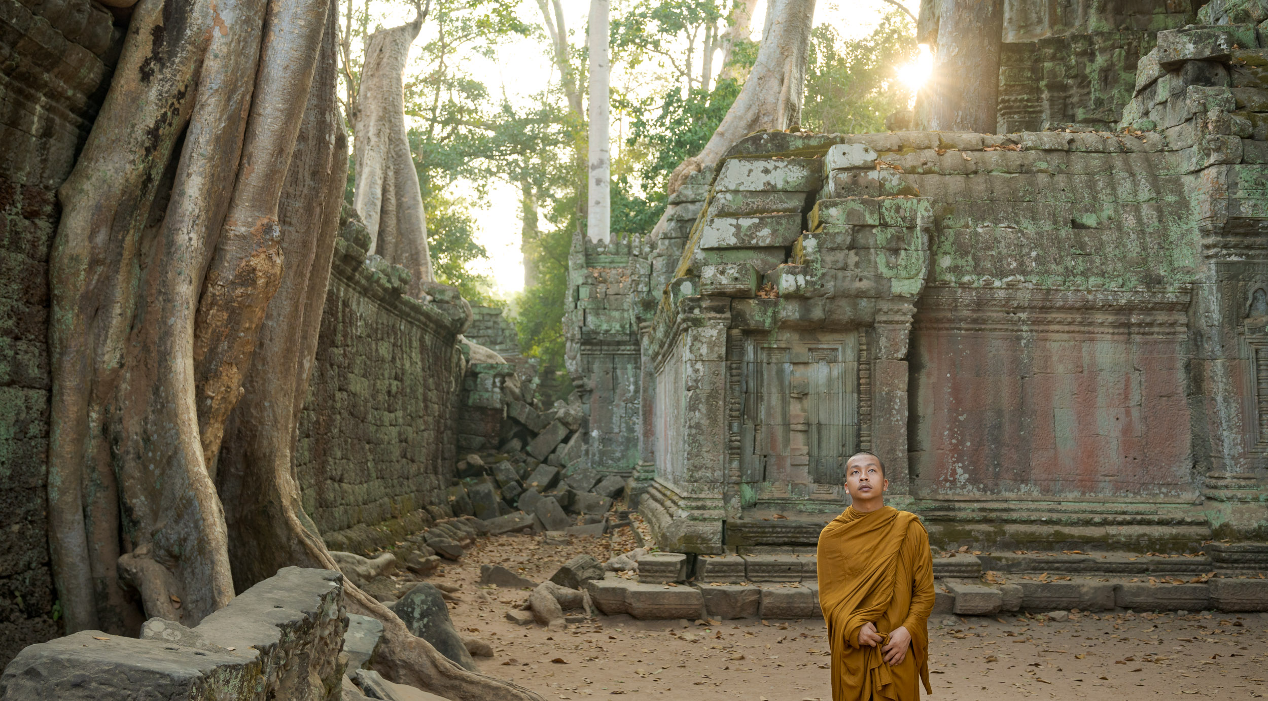 buddhist monk standing inside Ta Prom temple pavilion in Siem Reap, Cambodia