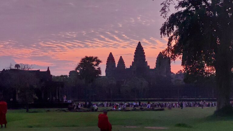 Angkor Wat sunrise photography with crowds at reflecting pool and quiet viewing area in foreground