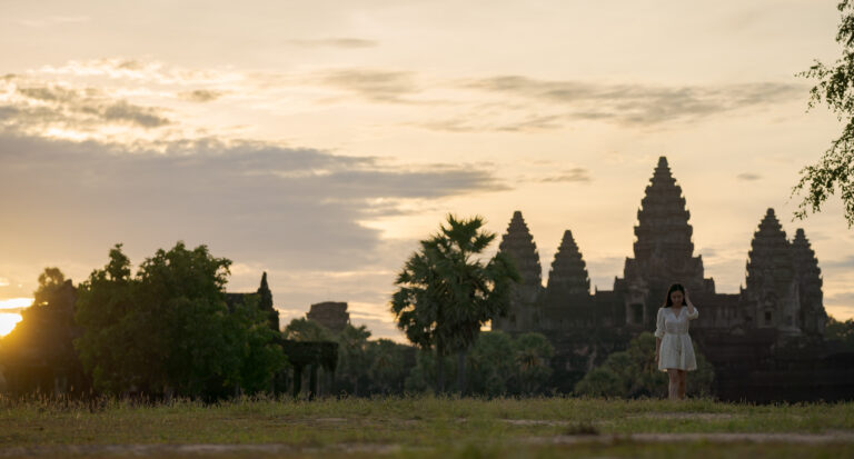 Angkor Wat silhouette at sunrise, photographed from ground level with grass in the foreground"